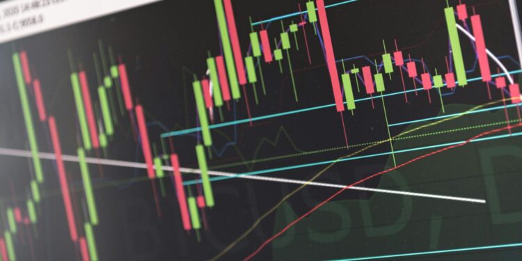 A soldier in uniform looks at a screen displaying stock market charts and prediction market data.