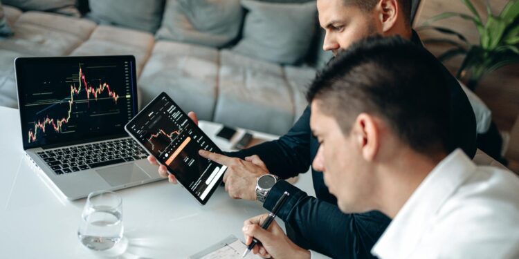 Two professionals discussing blockchain technology with digital graphs and charts in the background.