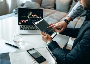 Two professionals discussing stock tokenization over digital charts and cryptocurrency graphics.