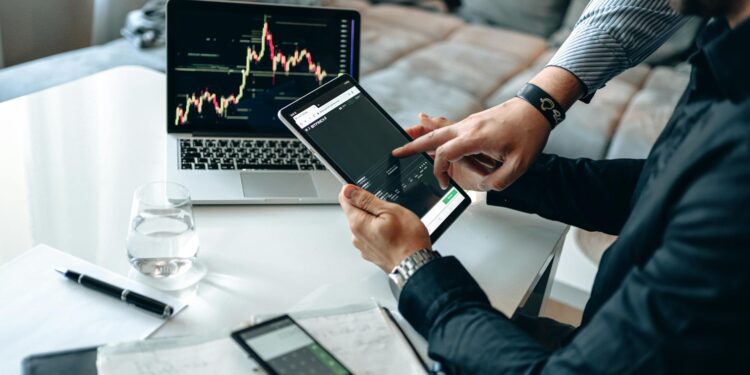 Two professionals discussing stock tokenization over digital charts and cryptocurrency graphics.