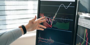 A financial analyst examines a chart showing XRP price trends and ETF performance.