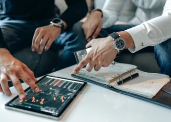 Crypto traders reviewing tax documents with graphs and financial data on their screens.