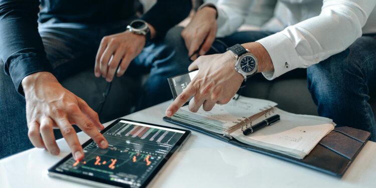 Crypto traders reviewing tax documents with graphs and financial data on their screens.