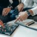 Crypto traders reviewing tax documents with graphs and financial data on their screens.