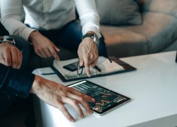 Two business professionals discussing cryptocurrency with digital graphs in the background.