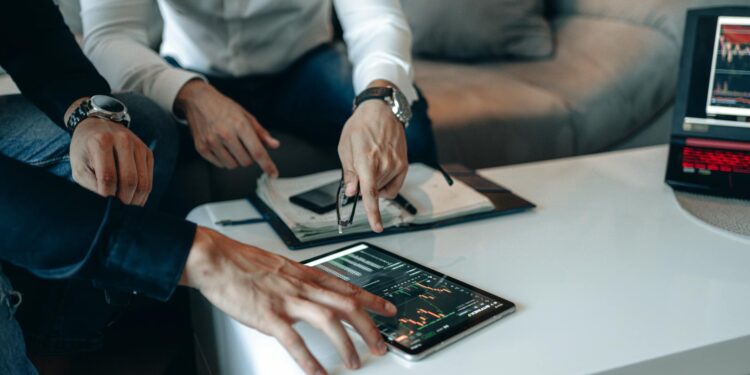 Two business professionals discussing cryptocurrency with digital graphs in the background.