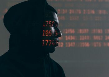 A hacker in a dark hoodie surrounded by digital code, highlighting cloud security breaches.