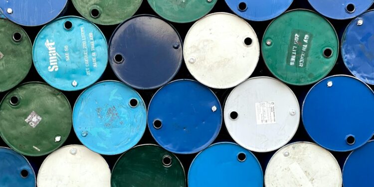 Oil barrels and Bitcoin coins juxtaposed with a US Navy ship in the background.