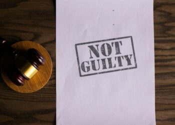 A gavel rests on a legal document with cryptocurrency symbols, symbolizing regulatory challenges.