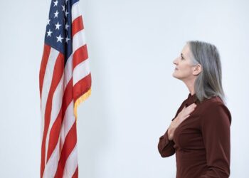SEC Chair speaking at a podium with crypto symbols displayed in the background.