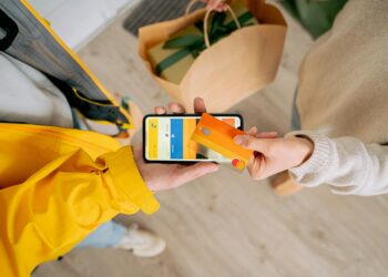 A DoorDash delivery worker holding a smartphone displaying a stablecoin payment app.
