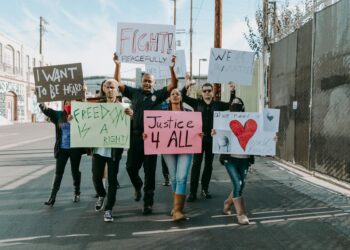 Protesters holding signs during a march against ICE shooting in California.