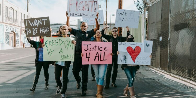 Protesters holding signs during a march against ICE shooting in California.