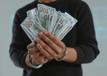Woman in handcuffs outside courthouse, involved in Bitcoin fraud case.