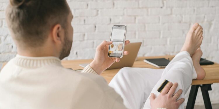 A person using a smartphone to make a food order with crypto payment options visible.