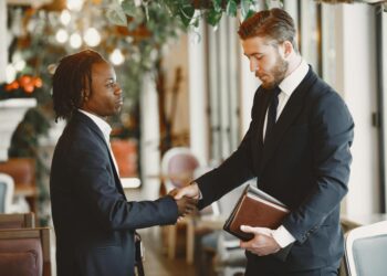 A handshake between business leaders set against a digital prediction market backdrop.