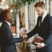 A handshake between business leaders set against a digital prediction market backdrop.