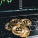Paul Atkins speaking at a podium with a backdrop of financial charts and cryptocurrency symbols.