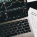 Cryptocurrency trading platforms logos with a financial graph in the background.