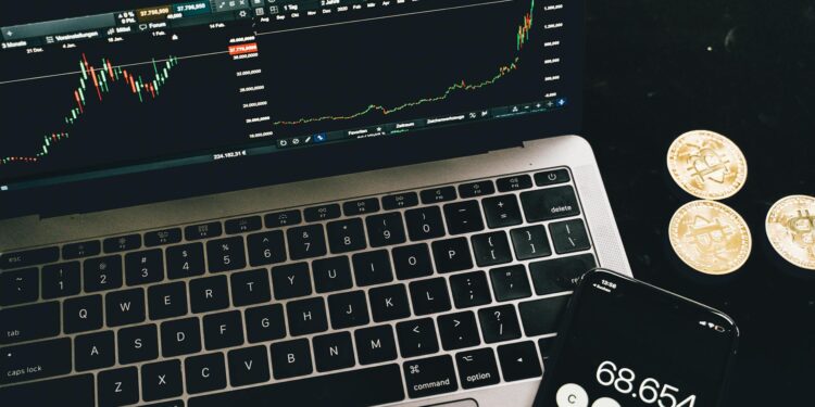 Bitcoin coins arranged beside a calculator and financial graphs, symbolizing ETF investments.