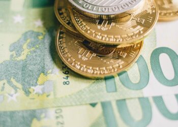 Euro banknotes and cryptocurrency coins on a financial report background, symbolizing regulation.