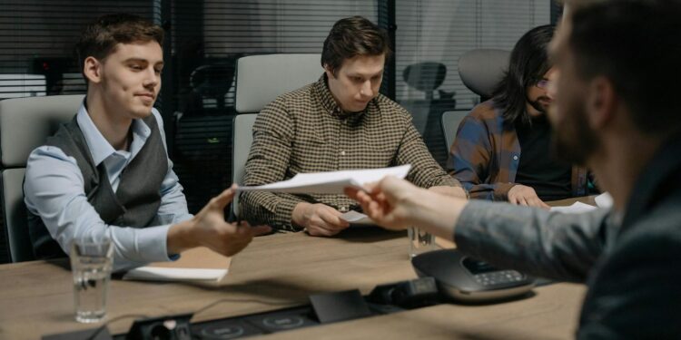 Business meeting with individuals discussing financial documents and cryptocurrency regulations.