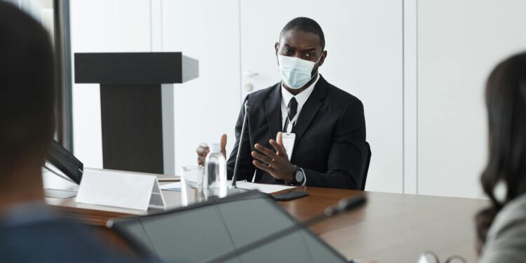 Hegseth speaking at a news conference, Army Chief George seated behind him, tense atmosphere.
