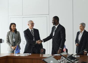 Executives from Startale Group and Sunnyside Labs shake hands in a tech conference setting.