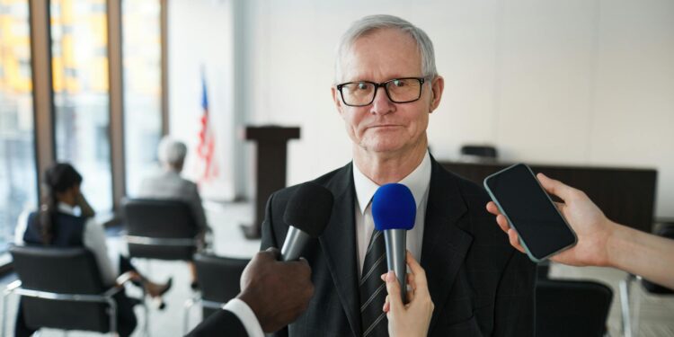 Eric Swalwell speaking at a press conference, with reporters and cameras in attendance.
