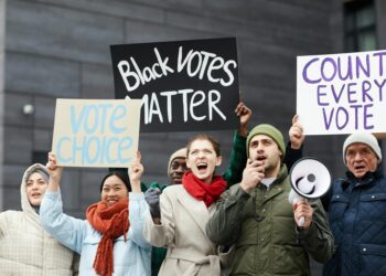 Protesters holding signs advocating for crypto regulations outside a government building.