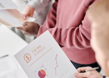 A group of politicians discussing regulations over a financial document with charts and graphs.