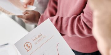 A group of politicians discussing regulations over a financial document with charts and graphs.