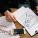 An investor examines financial documents, symbolizing the threat of impersonation scams.