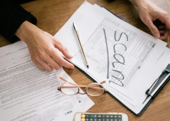 Financial advisor reviewing crypto tax forms with a calculator and laptop.