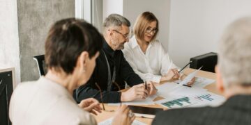 Small crypto firm employees discussing compliance documents and financial regulations.