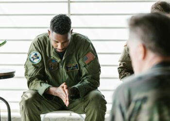 Uniformed soldier in handcuffs at a military base, reflecting insider trading concerns.
