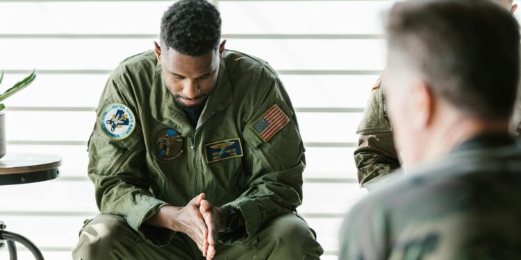Uniformed soldier in handcuffs at a military base, reflecting insider trading concerns.