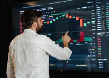 A financial analyst examines charts displaying cryptocurrency trends and ETF performance.
