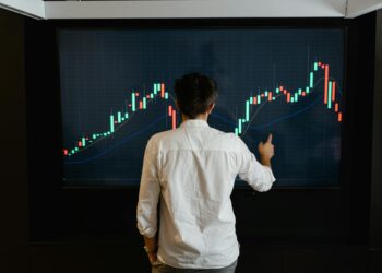 A trader analyzes Bitcoin charts on a digital screen with financial data and graphs visible.