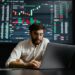 A trader analyzes cryptocurrency charts on a laptop with Bitcoin logos in the background.