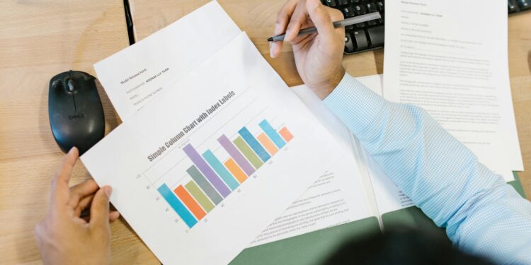 A financial analyst reviewing charts with Bitcoin symbols and ETF documents on a desk.