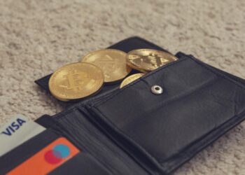 A digital illustration of a cracked cryptocurrency wallet with coins spilling out.