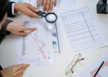 Office workers reviewing financial reports with graphs reflecting declining revenue trends.