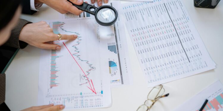 Office workers reviewing financial reports with graphs reflecting declining revenue trends.