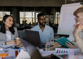 Marketing team meeting with crypto graphics and charts in a modern office setting.