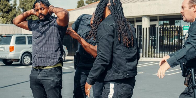 Police arresting a cryptocurrency founder outside a corporate building amidst news coverage.
