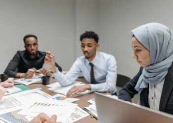 Employees in a meeting room appear concerned as Meta announces significant layoffs.