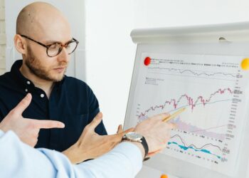 Two state employees discussing regulations with a prediction market chart in the background.