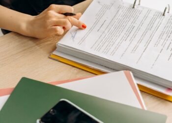 A person examines cryptocurrency symbols and regulatory documents on a desk.