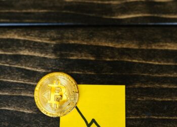 Stacks of cryptocurrency tokens with a downward arrow, symbolizing market decline.